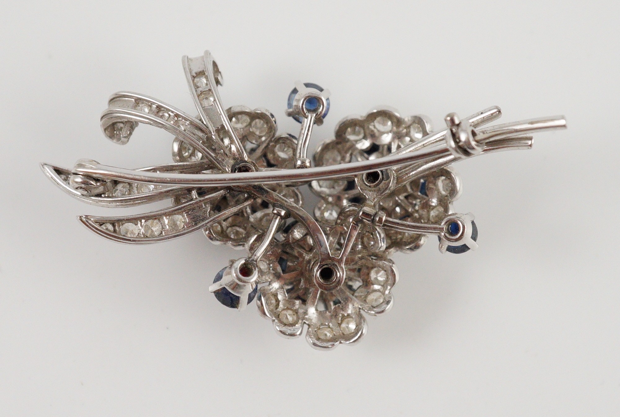 A white gold, sapphire and diamond cluster set floral spray brooch
